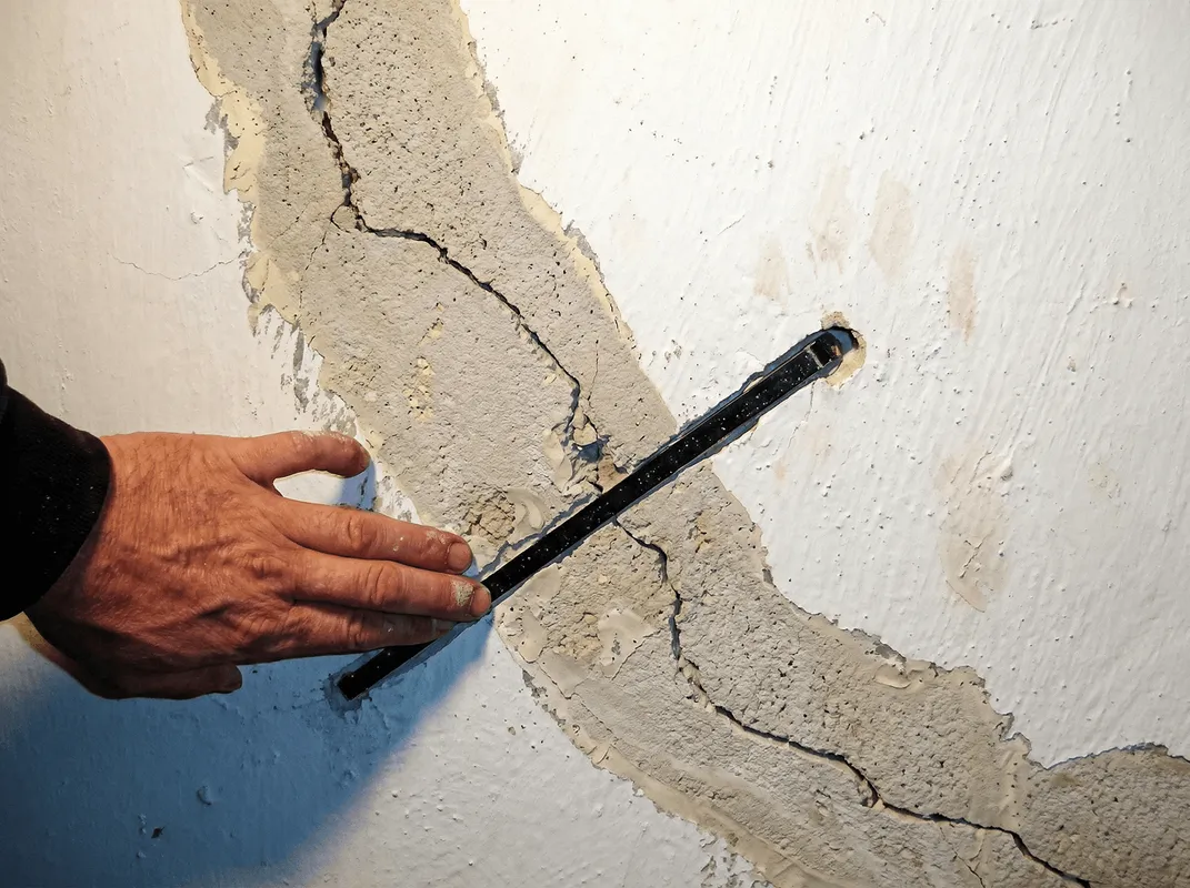 A wall with a large crack is being inspected by a professional in Santa Ana, CA